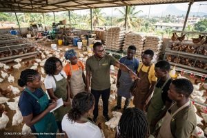 A Donguté trainer briefing a group of agricultural students inside a poultry house in Limbe